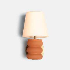 Decorative wall lamp with terracotta base and beige shade on a white background