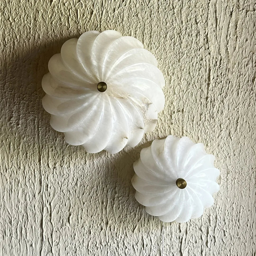 Two white decorative Spiral Alabaster Wall Lights with gold centers on a textured beige wall.
