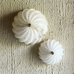 Two white decorative Spiral Alabaster Wall Lights with gold centers on a textured beige wall.