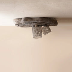 A rustic industrial ceiling light fixture with a rough, organic-shaped dark gray stone base and two cylindrical metal mesh shades
