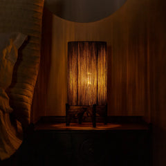 Ambra Table Lamp with warm glow in a dimly lit room with a textured wall