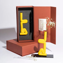 Yellow abstract Sirsasana Vase sculpture inside an open red box on a white background