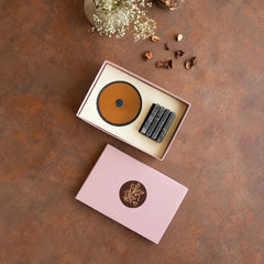 An open pink gift box on a brown surface, containing a round Yin Nut bowl in black marble and brass plus 4 matching rectangle coasters.