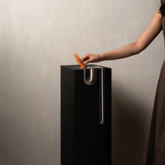 A modern black Bookcase Vase with a silver metal cup on top.