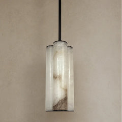 Single Pendant light fixture with cylindrical glass shades on a beige wall.