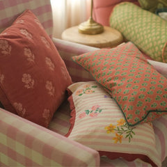Rosalia Dusty Rose Linen Oblong Cushion Cover layered with cushions on armchair, angled view
