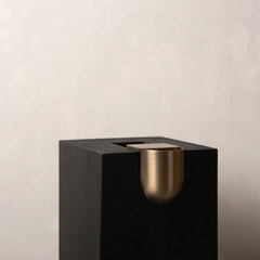 A matte black Bookcase Vase with a brushed brass cup-shaped holder mounted on the front.