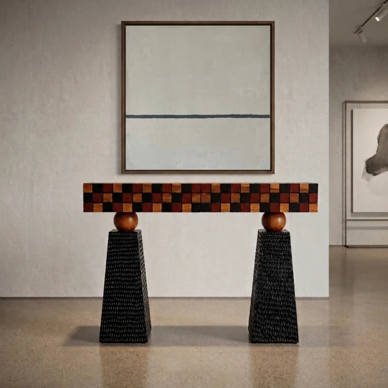 Tessaro Console Table with checkered mosaic wood front and textured black pedestals in a gallery room