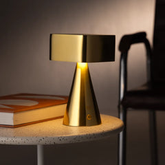 Gold table lamp on a round stone surface with a blurred chair in the background
