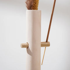 Beige ceramic vase with wooden base and incense holder on side on a light gray background