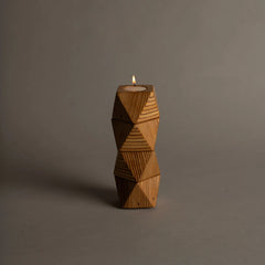 Chamfer Tealight made of marine plywood material with a lit candle on a gray background