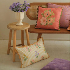 Rosalia Amber Linen Oblong Cushion Cover on floor beside wooden stool and cane bench