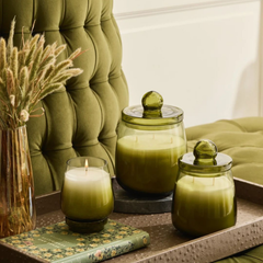 Cosmic Hues - Lid Jar Candle | Olive Green | Sage Cleanse, three sizes on a tray by a green tufted chair