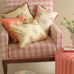 Rosalia Amber Linen Oblong Cushion Cover on gingham armchair beside striped pouf, wide view