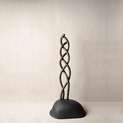 A metal finish decorative sculpture featuring a twisted, braided vertical stem rising from a rounded dome-shaped base.