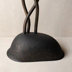 A dark charcoal-colored metal or decorative base with a rounded dome shape and three twisted vertical stems rising from the top.