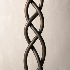 Decorative metal wall art with braided design on a beige background