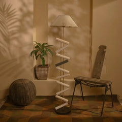 Room interior with a spiral lamp, plant, and wooden chair against a wall.