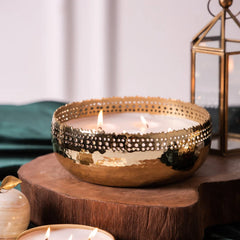 Close view of Jali Cutting Bowl Candle - Gold - Oud Rose, lit gold cut-work bowl on a wood slice