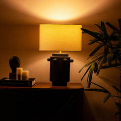 Slate Table lamp with warm light made of linen shade and black terracotta base on a wooden side table.