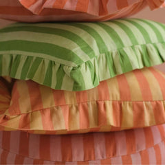 Linea Ruffle Amber Cotton Cushion Cover stacked with green and pink striped cushions, close view