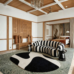 Modern living room with a black and white striped sofa, cowhide rug, and decorative wall panels.
