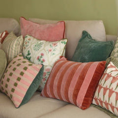A collection of decorative multi color Eden Rose Linen Cushion Covers in various patterns and colors arranged on a light beige sofa.