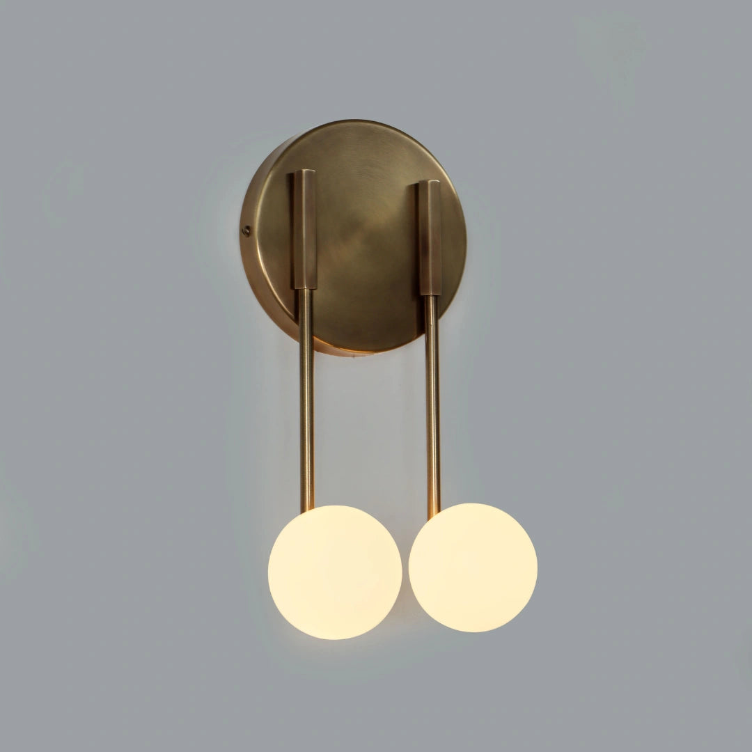 Brass loop wall sconce with two round lights on a gray background