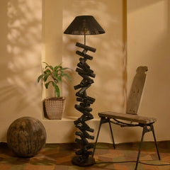 Twisted wooden floor lamp in a room with a plant and a chair.