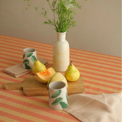 Linea Ruffle Amber Cotton Table Cover with fruit on wooden board and vase, angled close view