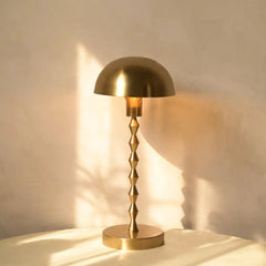 Lumo Table Lamp in gold lampshade casting a warm glow on a neutral background