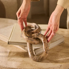 Nolyn Chain - Hands Arranging Linked Marble Chain on Books