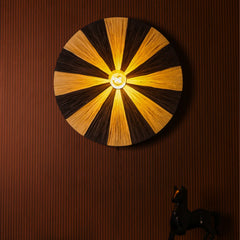Fiore wall lamp with black and natural raffia in circular design sunburst, casting warm glow.