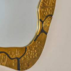 Gold decorative wall mirror with intricate patterns on a plain background