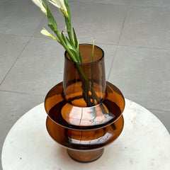Decorative brown glass vase with a reflective interior on a white surface.