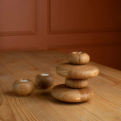 Stack of Pebbled Tealights candle holders on a wooden surface with a warm brown background