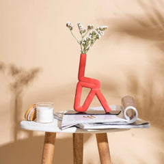 Red Trikonasana ceremic Vase with flowers on a small table against a beige background