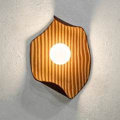Hexagonal wall light fixture with striped design on a textured wall.