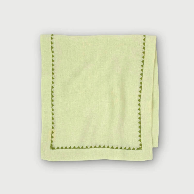 Mirage Pistachio Linen Table Runner folded, showing green embroidered triangle border