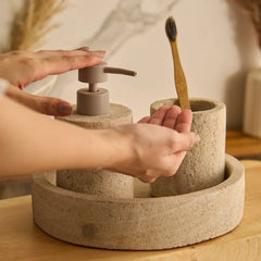 Dispenser Set - Indian Travertine - In Use, Hands at Pump with Bamboo Toothbrush in Tumbler