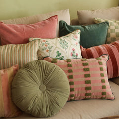 A collection of decorative throw pillows in various colors and patterns, including stripes, florals, and textured plaid, arranged on a beige sofa.