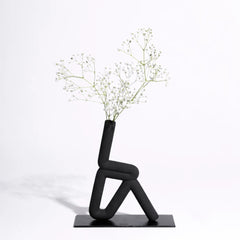 Black abstract vase with a plant on a white background