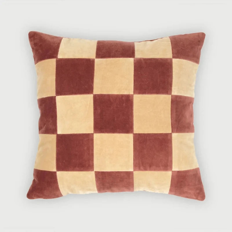 A square throw pillow with a checkered pattern in dark reddish-brown and light beige velvet, shown against a plain light gray background.