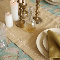 Mirage Sand Linen Table Runner with brass candlesticks, glass decanter and plates