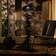Unique floor lamp in a dimly lit room with a chair and plant