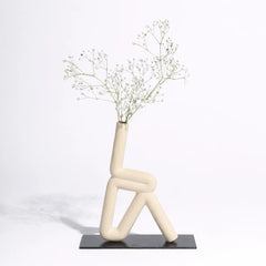 Modern ceramic vase shaped like a person with dried flowers on a white background