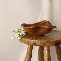 Wooden organic bowl on a wooden stool with a neutral background