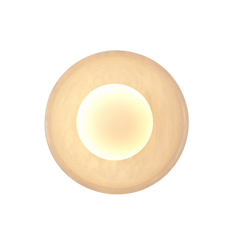 A wall sconce with a round, mottled white stone shade, illuminated from within, mounted on a brass fixture.