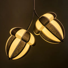 Acorns Pendant Lamp showing  lampshades hanging on black metal rod with a warm glow on a dark background