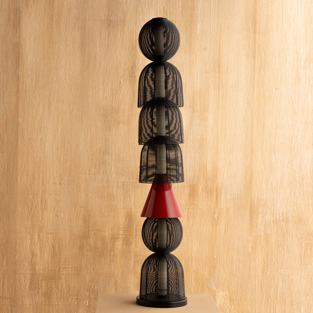 Decorative Totem Black Floor Lamp with stacked black and red geometric shapes on a wooden background